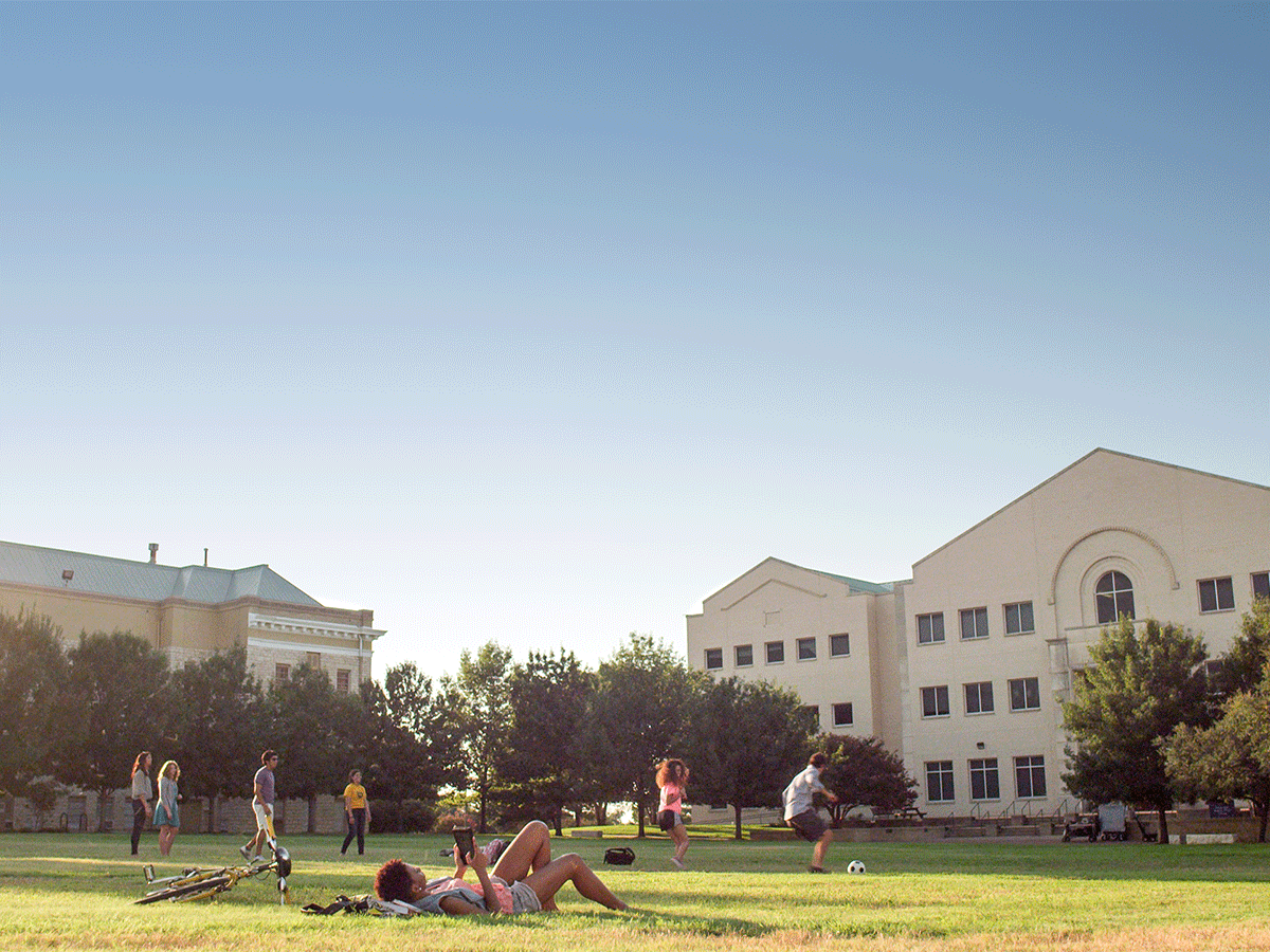 Image of a campus quad with students relaxing on the lawn