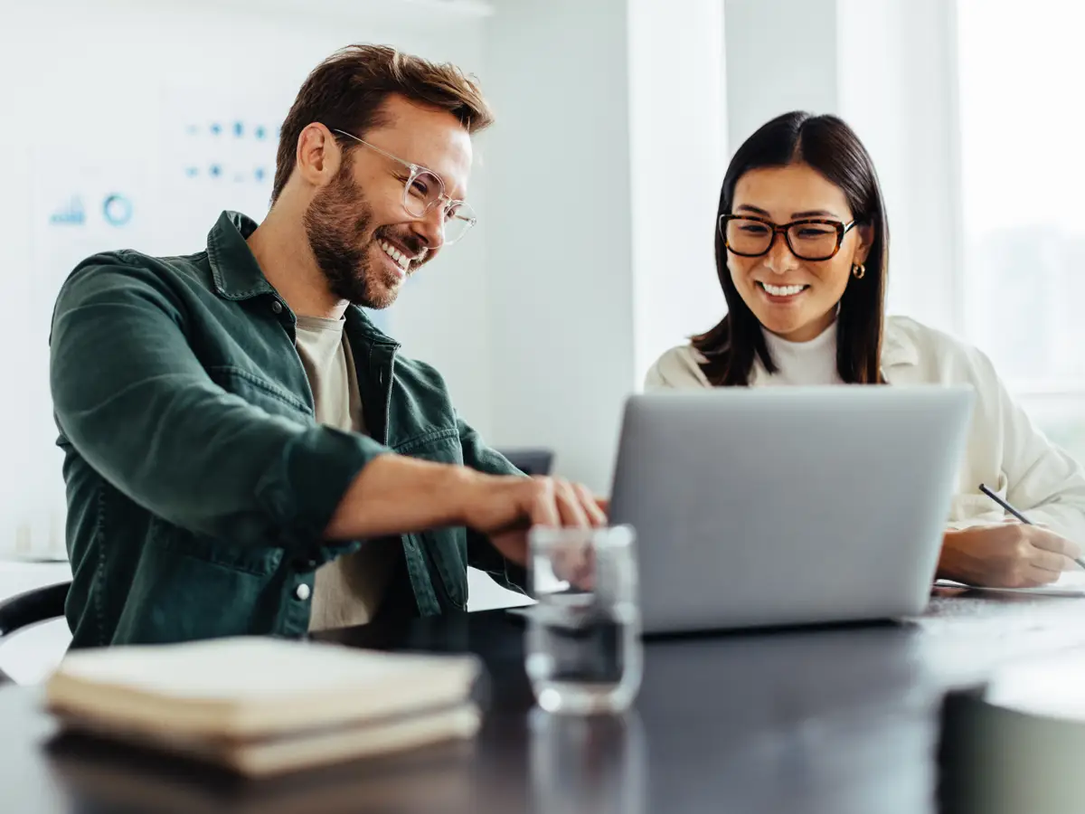Two casually dressed business people collaborating on a laptop
