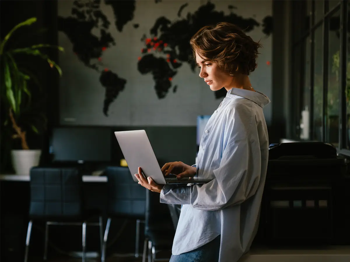 business woman standing and holding her laptop while in deep concentration