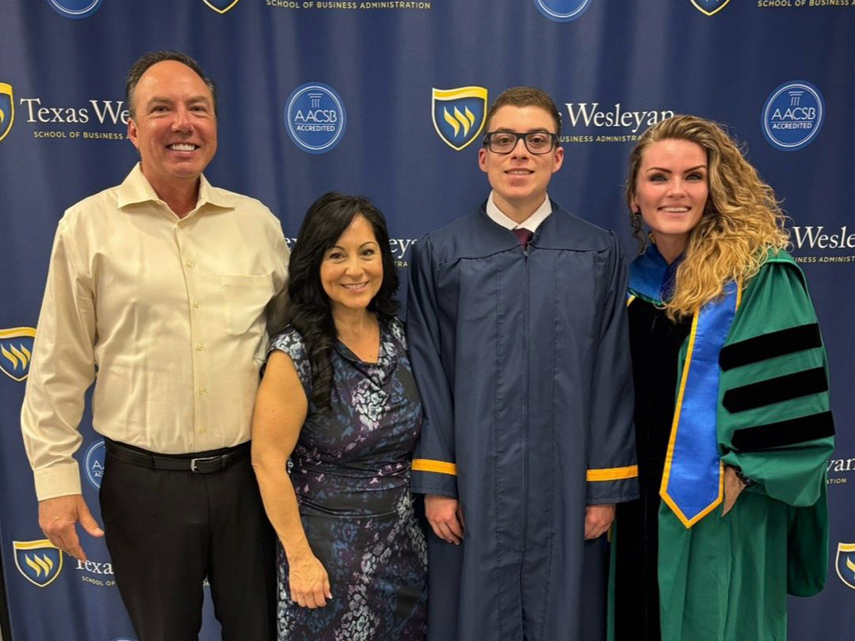 MBA faculty standing with graduate