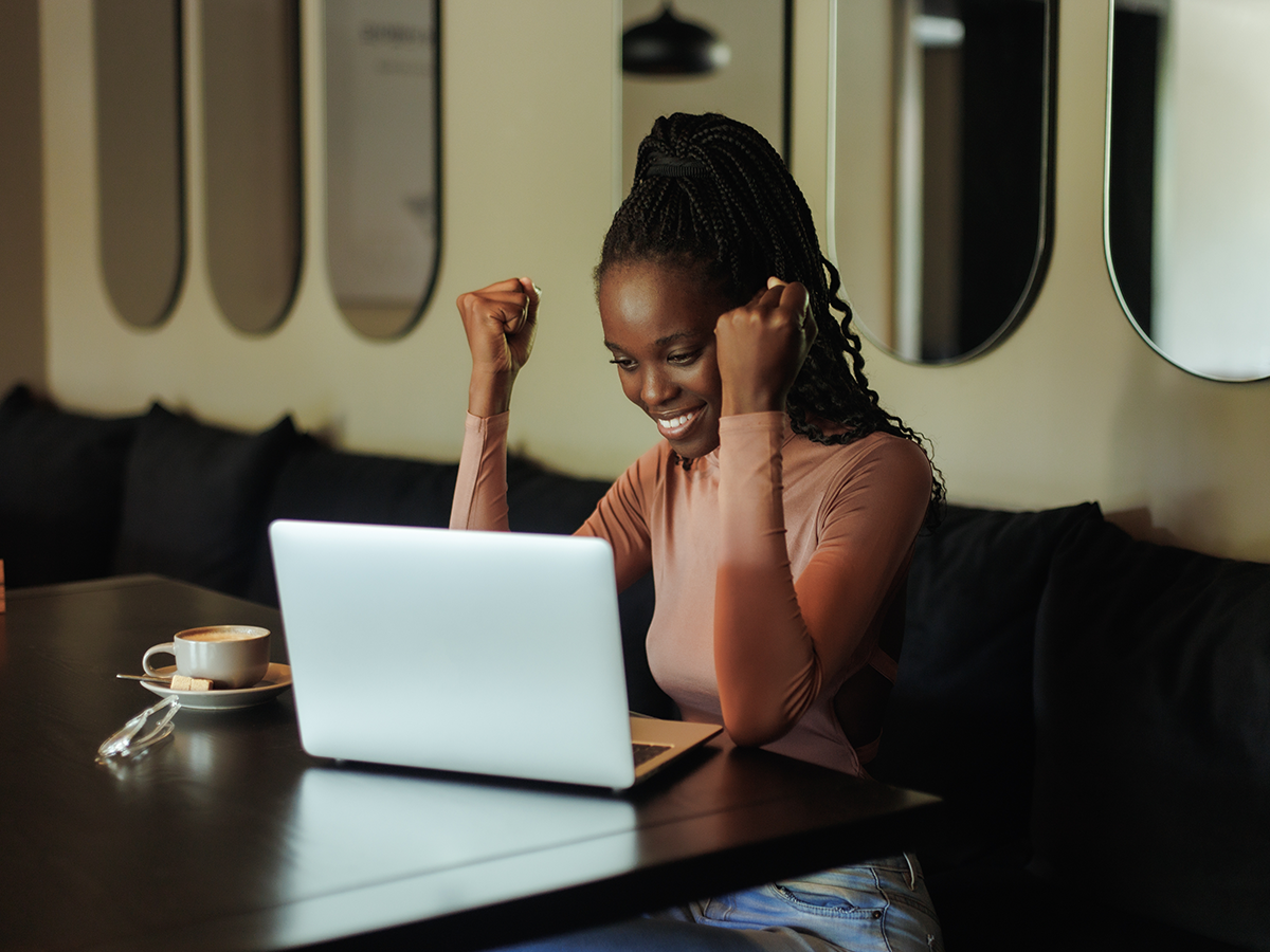 Woman celebrating her success in front of a laptop