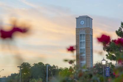 Campus clock tower with red flowers