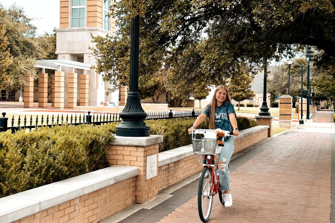 Student rides a bike down Rosedale St. on campus