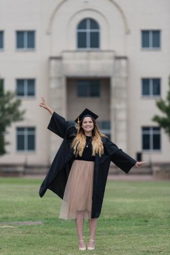 Erika Leal poses in cap and gown in front of The West Library