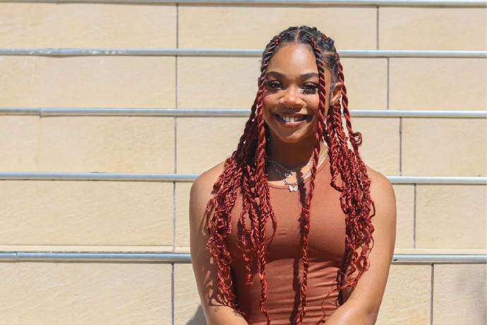 Starashia sits on the steps of the admin building at Texas Wesleyan University