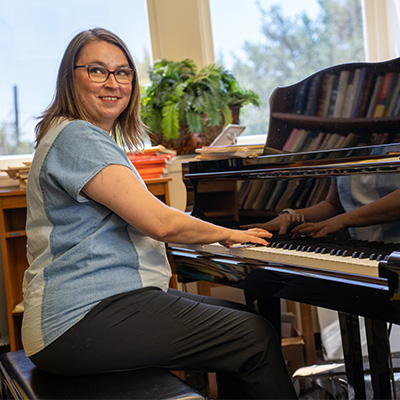 Mary-Margaret Soknich sitting at her piano smiling