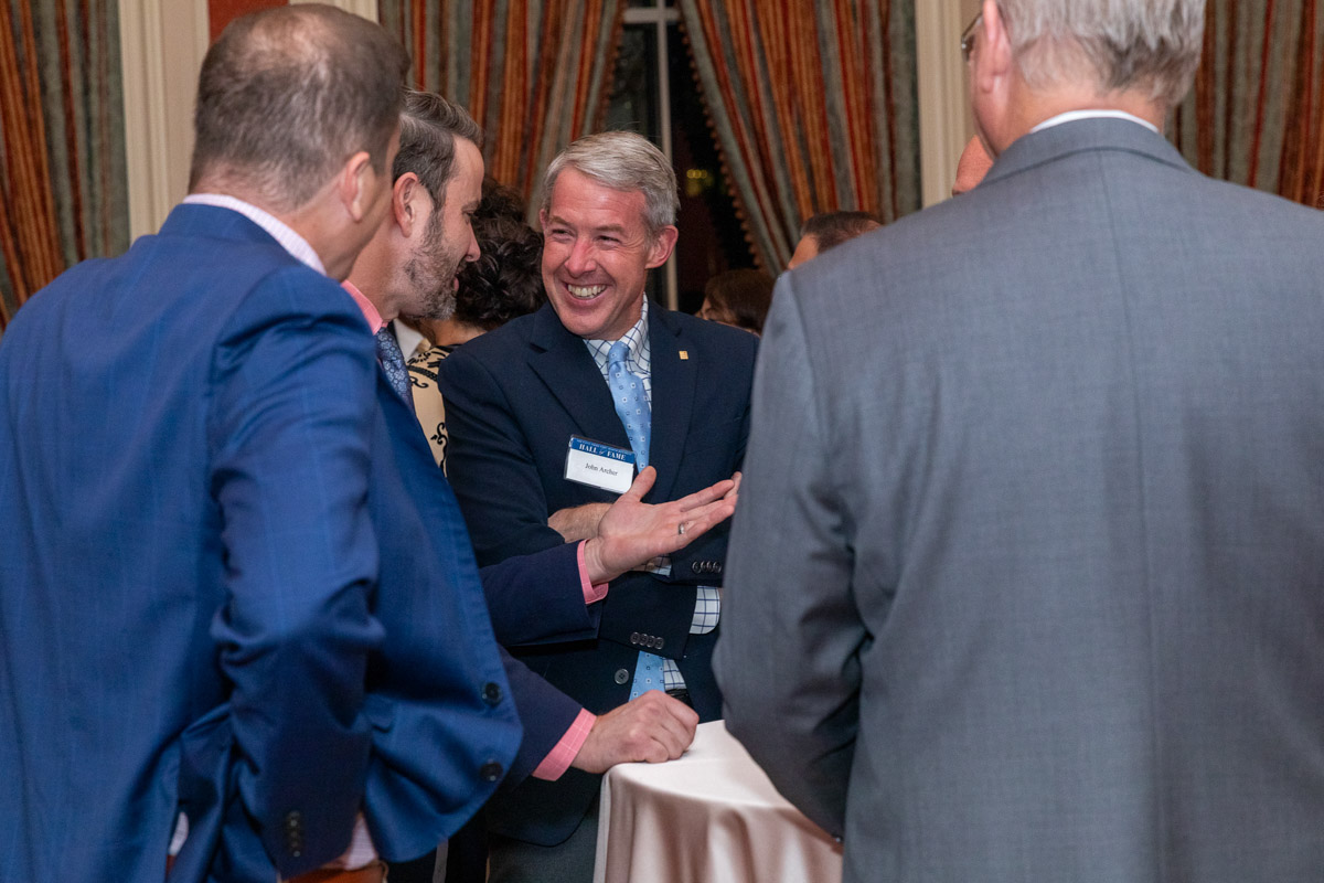 Man with white hair happily shakes hands with other men