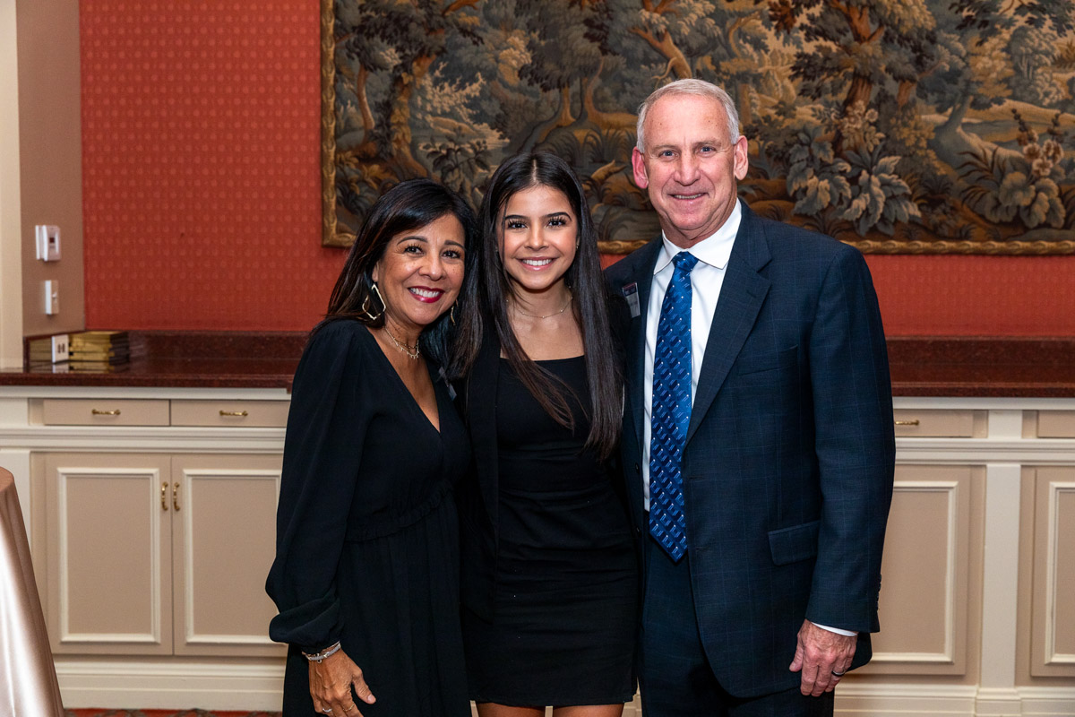two well dressed women and a man pose for a photo together