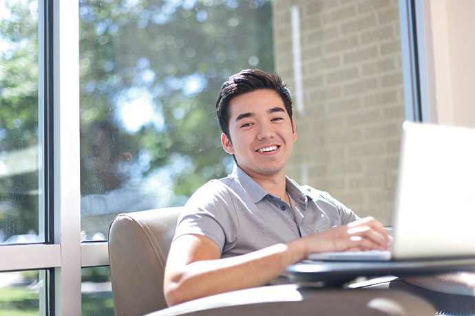 Photo of smiling student studying on a laptop.