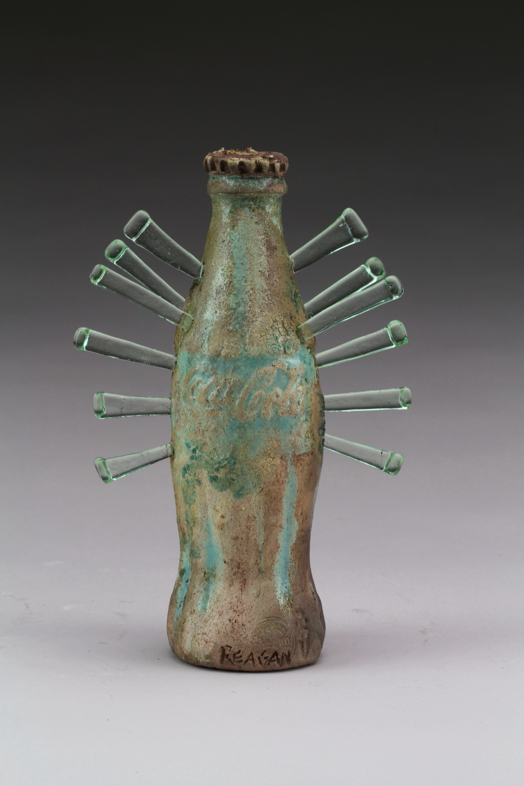 A sculptural ceramic Coke bottle with spikes sticking out the sides. 