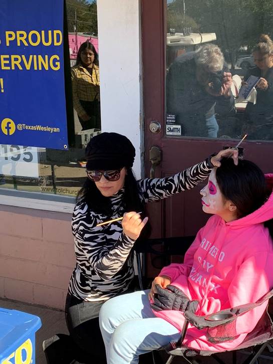 A child gets their face painted at the Texas Wesleyan table at the Dia de los Muertos festival