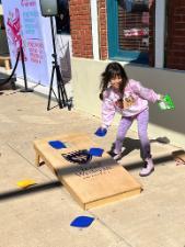 A child plays cornhole with a board featuring the Texas Wesleyan logo at the dia de los muertos festival