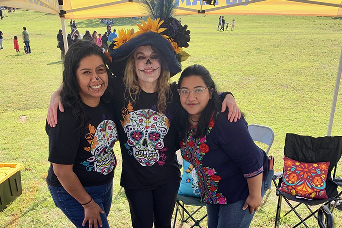 Dr. Amy Bell and two students pose at the 2023 Dia de los Muertos parade