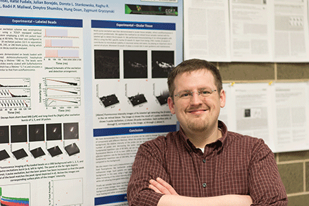 Dr. Ryan Rich stands in front of his research poster.