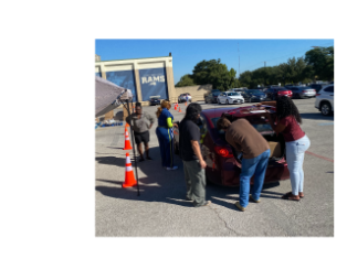Student volunteers loading groceries into cars.