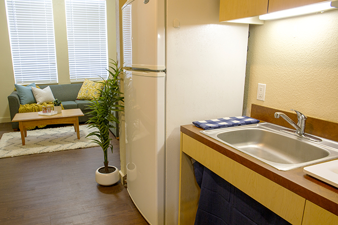 A dorm kitchenette showing sink and fridge.