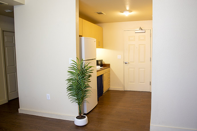 Dorm entryway with hardwood floors and kitchenette.