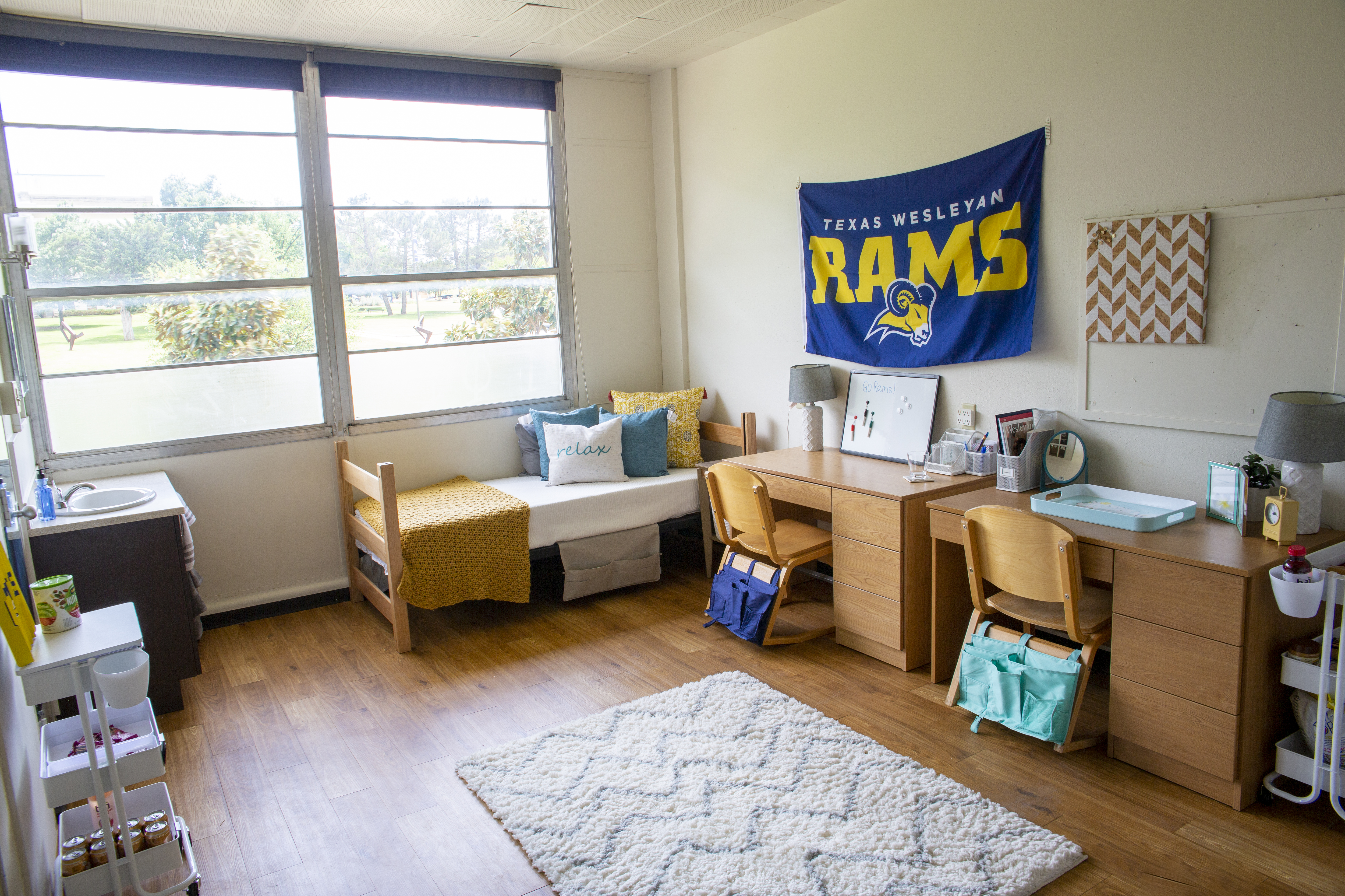 Student's decorated dorm with bed and desk on window side.