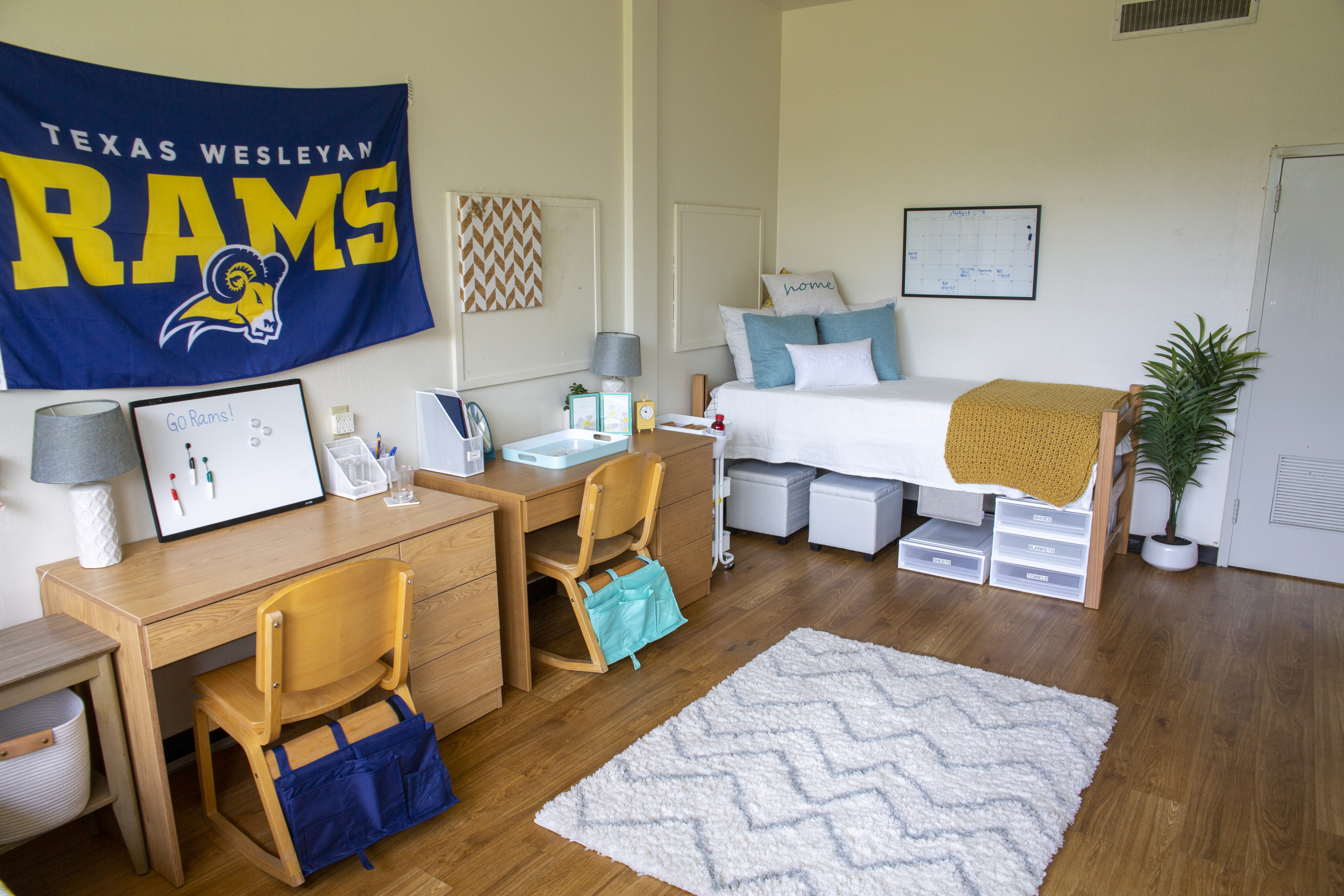 Student's decorated dorm with bed and desk on entrance side.