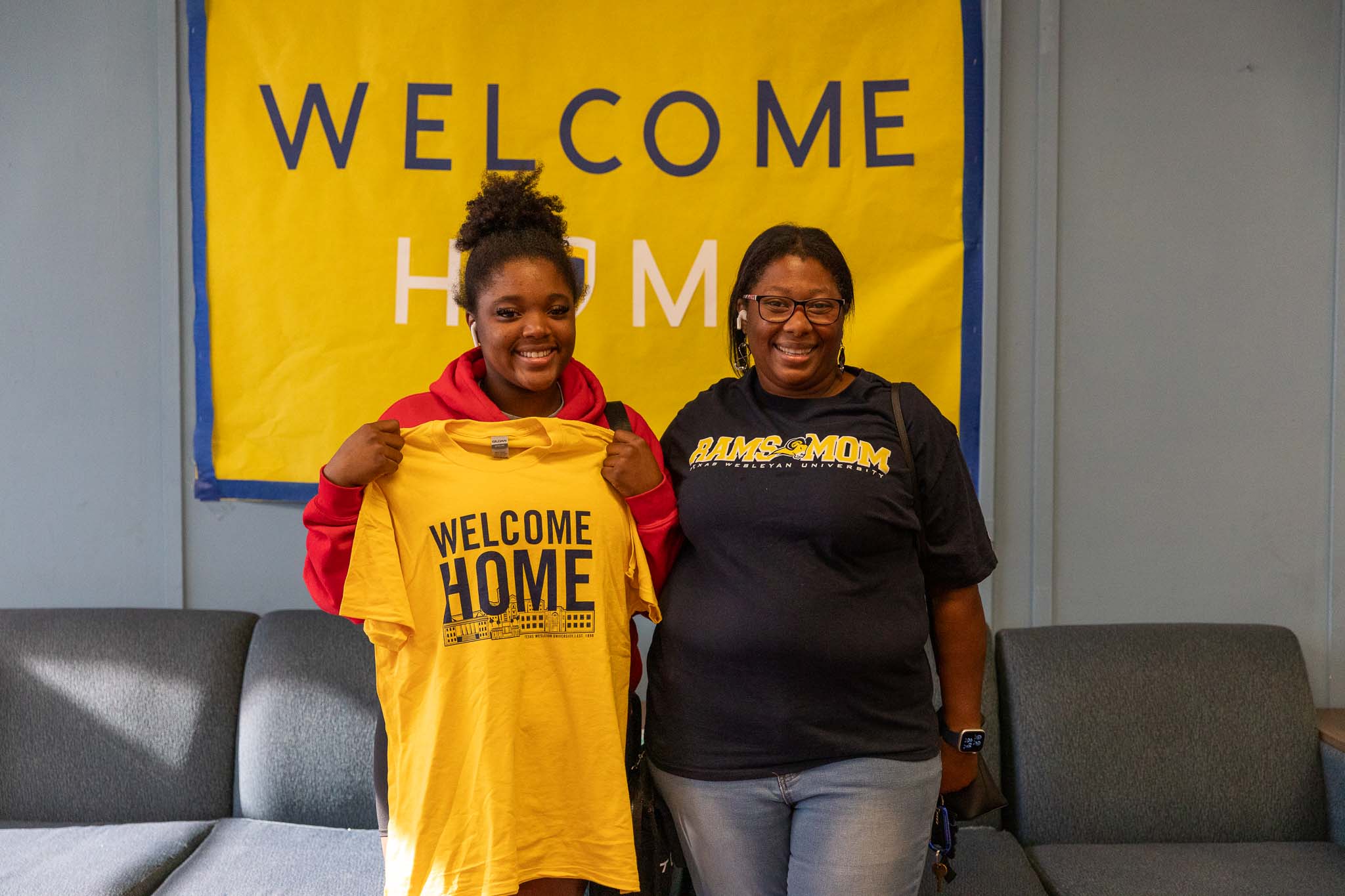 New student holds up her move in day shirt and poses with her mom