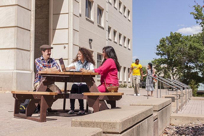 Photo of students sitting around a picnic table in front of the West Library.